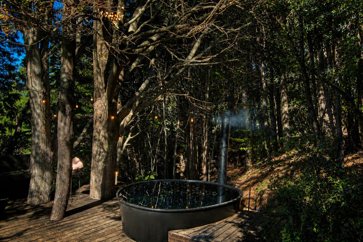 Hot tub de acero con chimenea entre &aacute;rboles